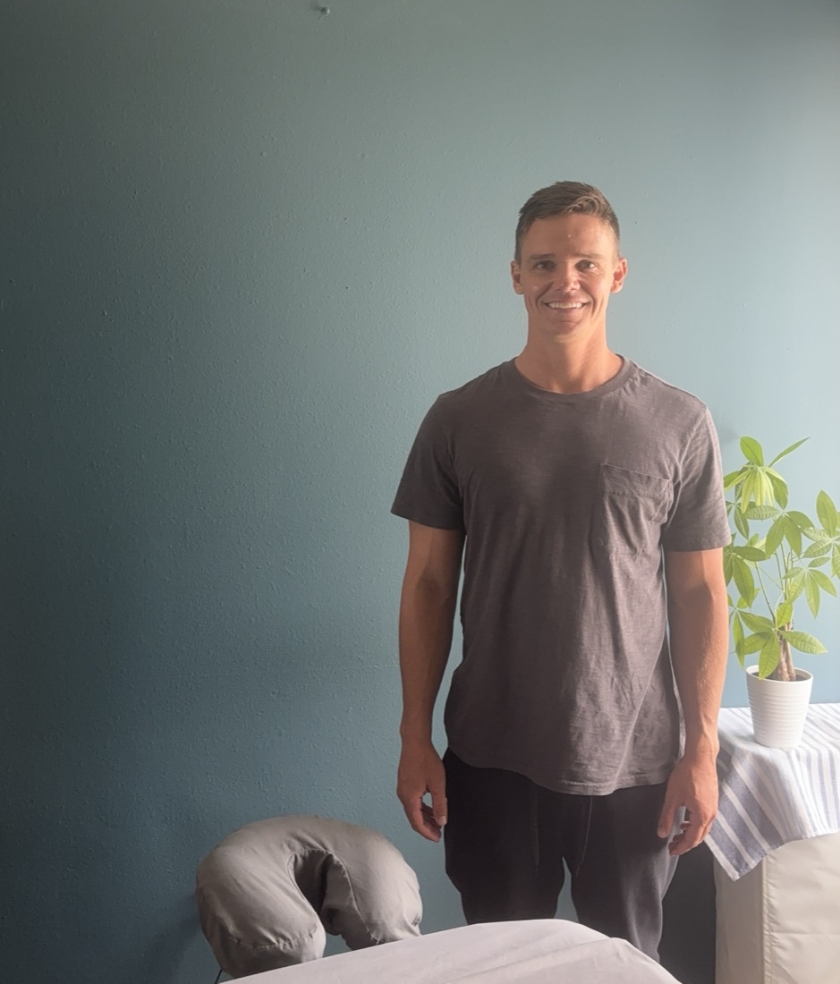 Nick standing beside his massage table in his Pacific Beach treatment room